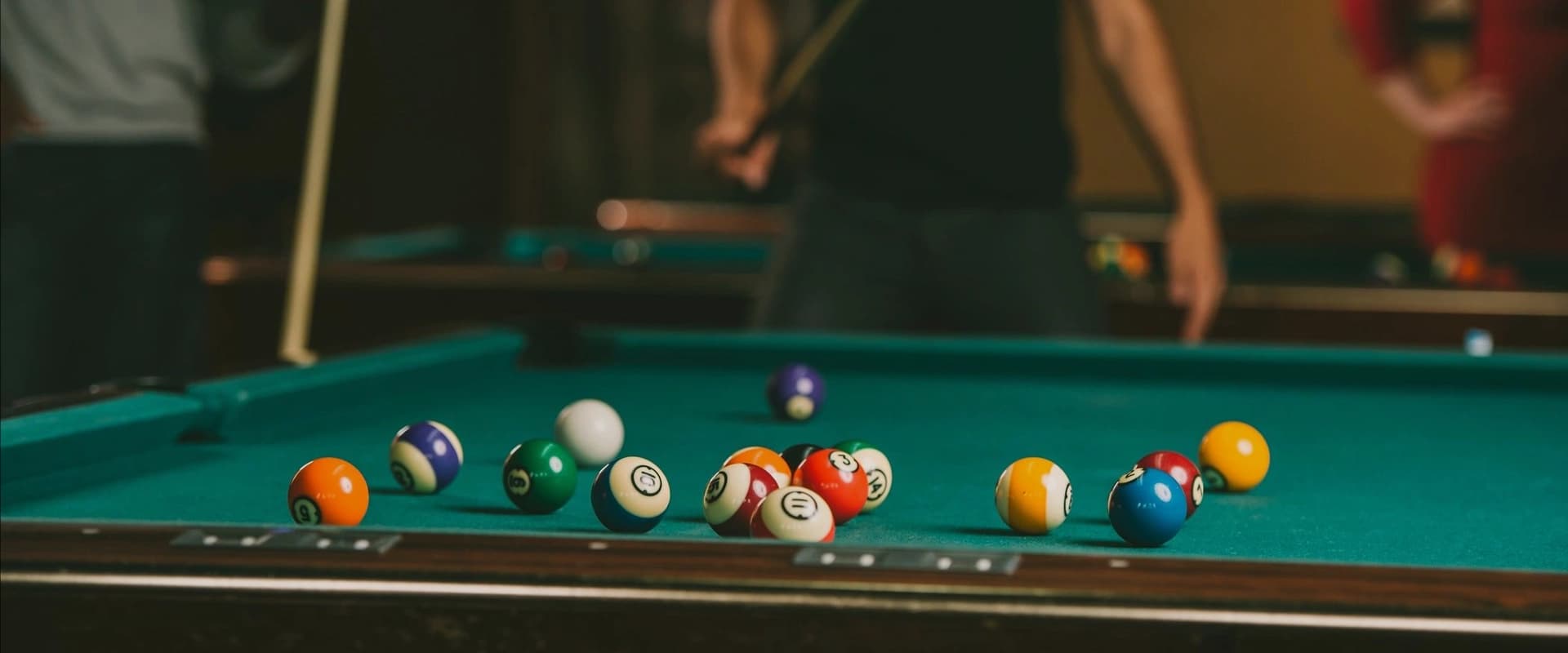 Racked pool balls on a felt table under bar lighting